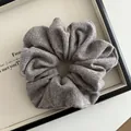 Close-up of a grey striped knit scrunchie on a tray showing soft fabric texture - Brown