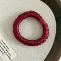 Detaillierte Nahaufnahme des burgunderroten Satin-Haargummis mit rotem Knopf auf Webmatte - Mit Zierschnalle / Burgunder Kleiner Haargummi