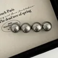 Macro view of four gunmetal mirror-finish spheres on a French vintage spring hair clip - Gray