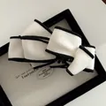 Detail of elegant black and white bow hair clip with textured fabric and classic edging - White