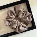 Close-up of mocha brown knitted scrunchie with soft ribbed texture and pleated detail - Brown