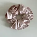 Gros plan sur un chouchou en satin rose champagne montrant la texture plissée et couture - Rose