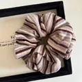 Dettaglio di scrunchie in maglia a righe retrò nei toni del caffè e della lavanda - Caffè Loto