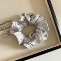 Vue détaillée d'un chouchou en satin gris plissé sur un plateau vintage - Gris Argent