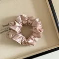 Détail d'un chouchou en satin plissé de haute qualité rose champagne à texture soyeuse - Rose