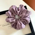 Detailed close-up of a purple striped fabric scrunchie with soft pleated texture and elastic - Purple Striped