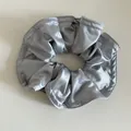 Détail rapproché du chouchou en satin gris argenté avec texture lisse et couture de bord - Bleu