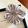 Close-up of grey fabric hair scrunchie with detailed red, black and gold stripes - Rice Red Black Striped