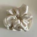 Detailed view of the soft cream satin fabric texture on this oversized hair scrunchie - Off White
