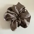 Macro shot of large satin scrunchie showing premium silky texture and champagne folds - Brown