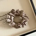 Gros plan sur un chouchou en satin doré champagne avec texture plissée élégante - Café au Lait