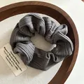 Detailed close-up of dark grey striped fabric scrunchie on a rustic wooden tray - Gray