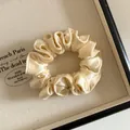 Détail du chouchou en satin doré champagne avec bords plissés dans un coffret cadeau - Jaune Lait