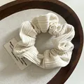 Close-up of cream striped knit fabric scrunchie with soft ribbed texture in a wooden tray - Off-white