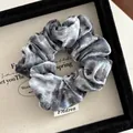 Detail of grey-blue velvet scrunchie showing soft texture and premium FMdrea woven label - Blue