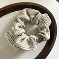 Detailed view of beige ribbed knit scrunchie texture on rustic wooden tray background - Light Green