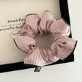 Nahaufnahme des rosa gestreiften Scrunchie mit Schleifen-Label in schwarzer Box - Rosa