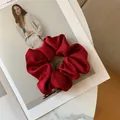 Macro shot of elegant deep red satin silk scrunchie on a stylish marble background - Burgundy