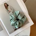 Detail showing mint green silk satin scrunchie with soft pleats on a fashion magazine - Mint