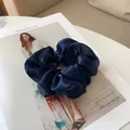 Détail macro d'un chouchou en satin bleu foncé au lustre soyeux sur un magazine - Bleu Marine