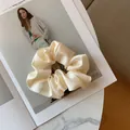 Macro shot of large beige silk scrunchie on fashion magazine with elegant texture - Cream White