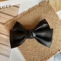 Detail of vintage black leather bow hair clip with lychee texture on aesthetic magazine - Black
