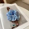 Détail d'un chouchou en satin bleu clair avec texture perlée sur un magazine de mode - Bleu