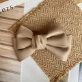 Close-up of khaki leather bow hair clip showing fine texture on a rustic background - Apricot