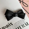Detalle del pasador de pelo con lazo de cuero sintético negro sobre fondo de revista de moda - Negro