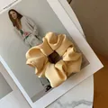 Close-up of cream satin silk scrunchie with soft pleats on a fashion magazine page - Yellow