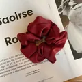 Detail of wine red crinkled satin scrunchie placed on a fashion magazine background - Burgundy