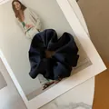 Detail view of a large matte navy blue silk scrunchie placed on a fashion magazine - Navy Blue
