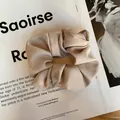 Détail d'un chouchou en satin élégant avec texture plissée douce sur fond de magazine de mode - Blanc Cassé