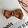 Detalle de horquilla de lazo en cuero PU marrón caramelo con textura de grano de lichi fino - Camello Claro