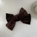 Detailopname van donkerbruine fluwelen strik haarclip met vintage textuur op witte basis - koffiekleur
