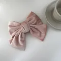 Detailopname van een elegante oudroze fluwelen strik haarspeld op een minimalistisch bureau - Roze