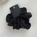 Detail view of black satin scrunchie with rhinestones on a wooden display tray - Black
