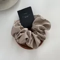 Detail of champagne satin scrunchie with rhinestones on a wooden tray with a black tag - Milk Tea
