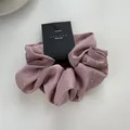 Detail of dusty pink satin scrunchie featuring delicate silver rhinestones and brand tag - Pink