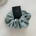 Detailed view of mint green satin scrunchie with rhinestones on black display card - Lake Blue