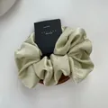 Macro detail of a light green satin scrunchie with rhinestones on a white background - Green