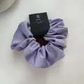 Detail of lavender satin scrunchie with sparkling rhinestones and branded tag - Purple