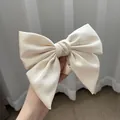 Large cream satin bow hair tie with silky texture held by hand to show premium size - Cream White