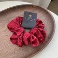 Deep red satin scrunchie with white polka dots and premium texture on wooden tray - Burgundy