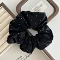 Macro detail of black velvet scrunchie with sparkling silver dots and soft texture - Black