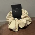 Close-up of cream velvet scrunchie with silver studs on a wooden display tray - Off White