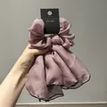 Dettaglio scrunchie in raso lilla con nastri lunghi e bordo nero a contrasto - Viola Loto