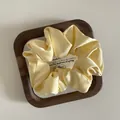 Elegant cream yellow satin scrunchie with silky texture in a wooden display tray - M / Yellow