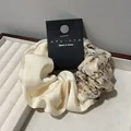 Detailaufnahme eines floralen Satin-Haargummis auf einem weißen Schmucktablett - Retro Blumen Patchwork Stil / Cremeweiß