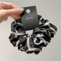 Dettaglio di uno scrunchie a scacchi con texture ondulata ed etichetta in mano - Stile Plaid Bianco e Nero (A12-1-2585) / Nero